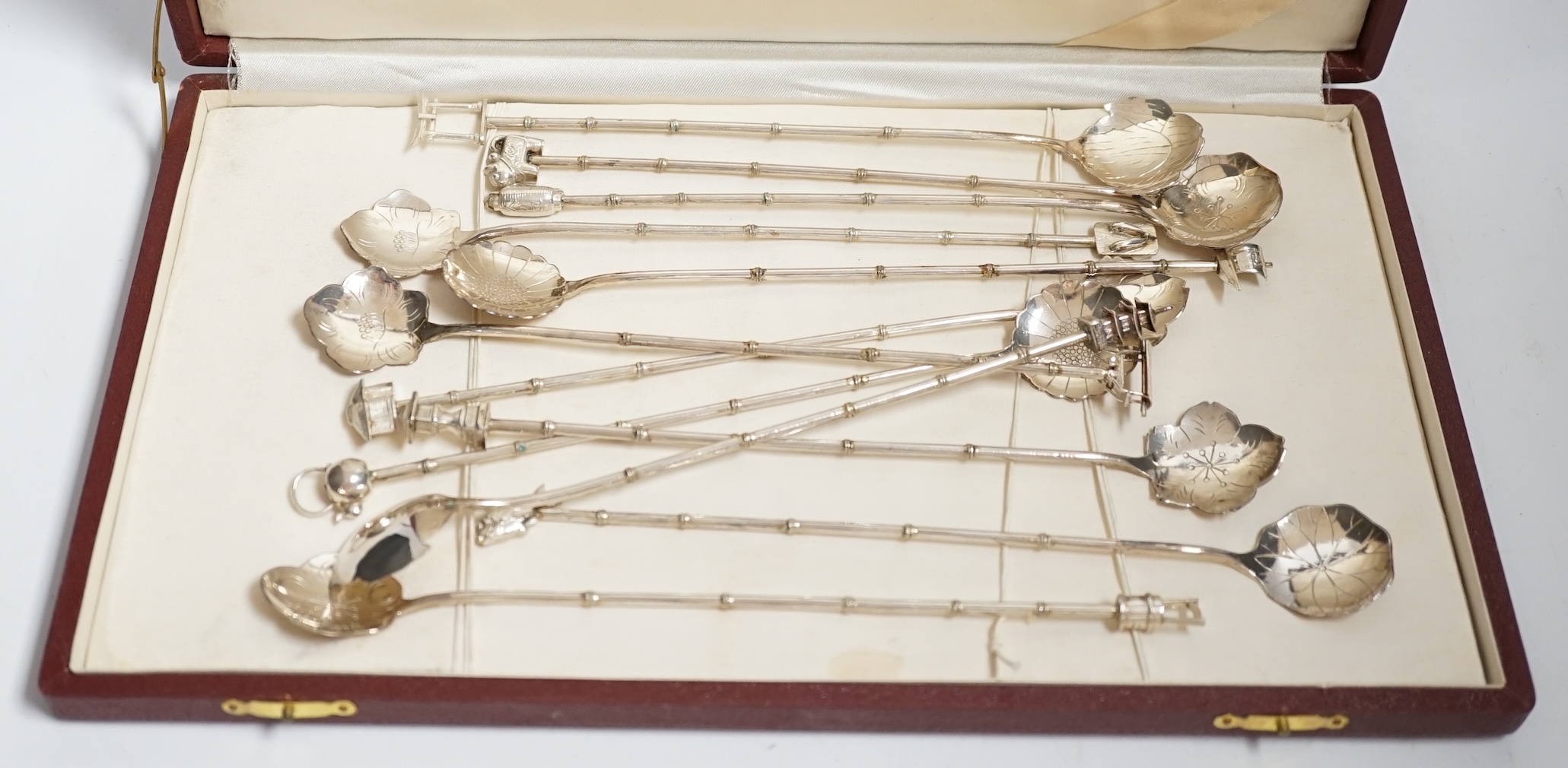 A cased set of twelve Japanese? white metal cocktail spoon, with differing terminals, 21.1cm.